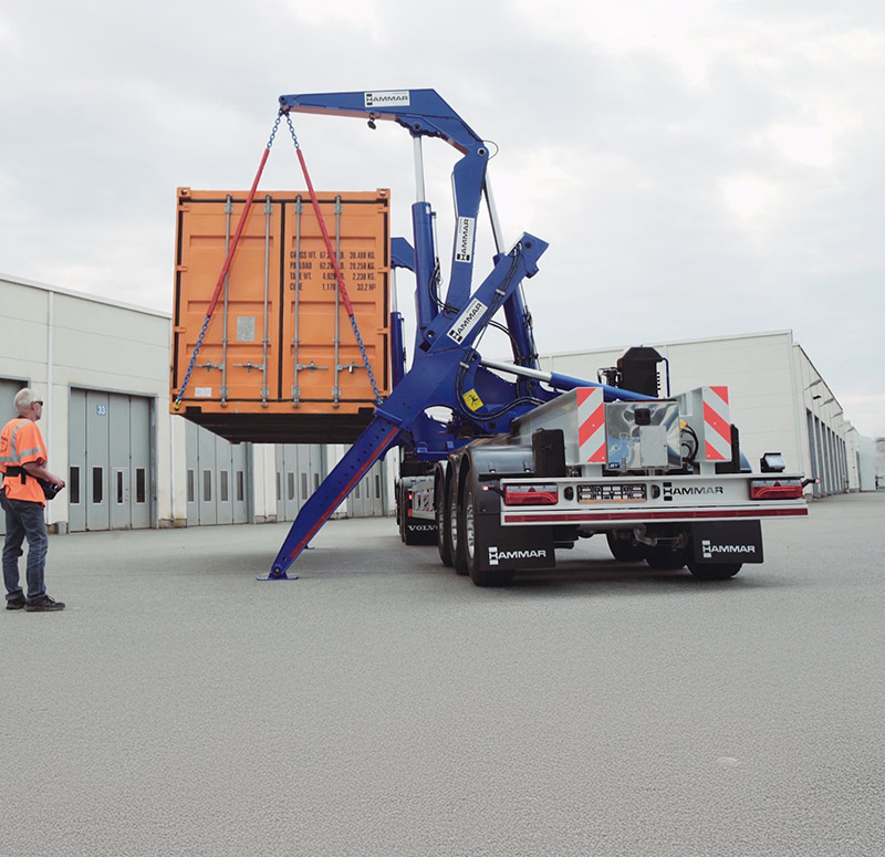 Hammar 195 sideloader lifting an orange container from-to ground level